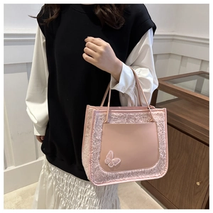 Pink plush tote bag with leather pocket and butterfly embroidery shown held by model