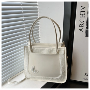 Close-up of white PU leather tote with plush fur trim and delicate butterfly embroidery