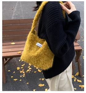Gros plan d'un sac cabas en peluche jaune gingembre avec étiquette blanche dans un parc