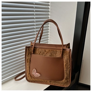 Detail of plush faux fur texture with smooth leather pocket and pink butterfly embroidery