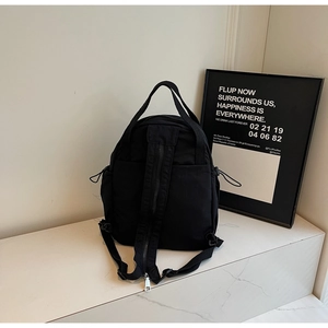 Détail du sac à dos en nylon noir avec poche zippée invisible au dos et cordons latéraux