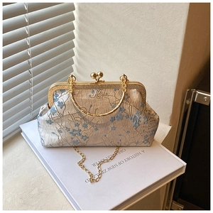 Detailed close-up of blue floral embroidery and golden metal frame clasp on a retro bag