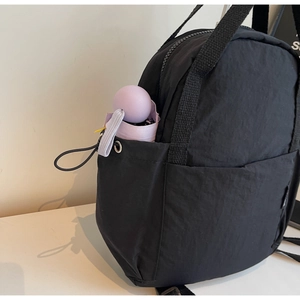 Détail de la poche latérale du sac à dos en nylon noir avec un mini parapluie mauve