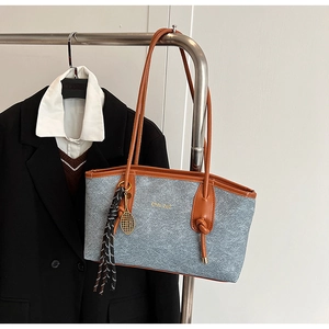 Close-up of felt tote bag featuring leather straps and decorative tennis racket charm