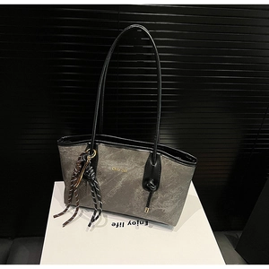 Detail view of large grey tote bag with marble texture and braided rope charm accessory