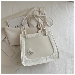 Detailed close-up of cream white PU leather tote with plush fur trim and blue butterfly embroidery