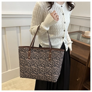 Detail of leopard print tote bag featuring brown leather handles and gold rivet accents