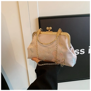 Detailed close-up of pink embroidery on retro clutch bag with golden chain strap