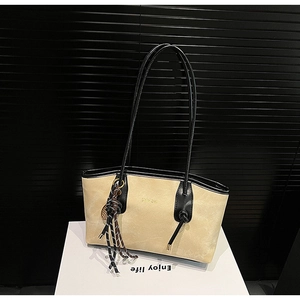 Macro detail of beige suede tote with gold logo and black leather trim accents