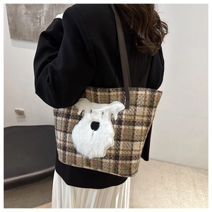 Detail of checkered tote bag with a 3D plush dog patch and brown leather straps