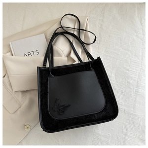 Detail of black PU leather tote with plush fur panels and butterfly embroidery