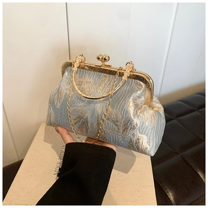 Detailed view of light blue floral embroidery on handbag with pearl clasp and gold chain