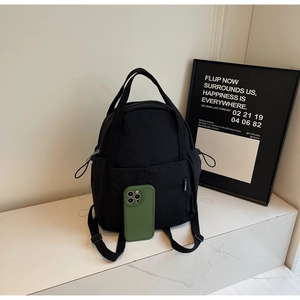Vue latérale du mini sac à dos en nylon noir avec poche latérale à cordon et poignée