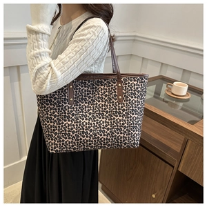 Detail of leopard print tote bag with brown leather straps and rivet accents