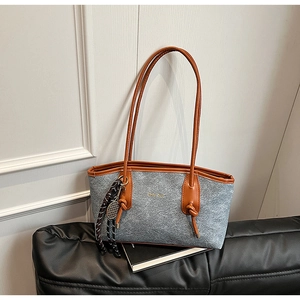 Detail of grey felt tote bag with brown leather straps and tennis racket pendant