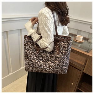 Fashionable leopard print tote bag with brown leather straps shown worn over the shoulder
