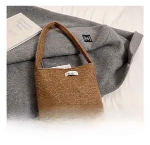Détail du tissu pelucheux caramel doux et de l'étiquette tissée sur le sac seau chic