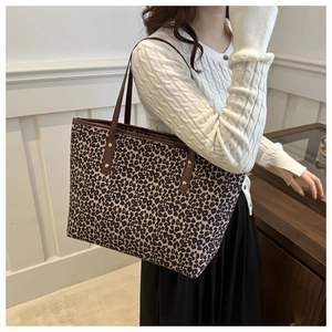 Detail of leopard print tote bag featuring brown leather straps and gold metal rivets