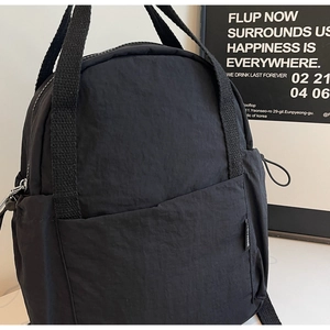 Détail d'un sac à dos en nylon noir avec bretelles tissées et poche latérale