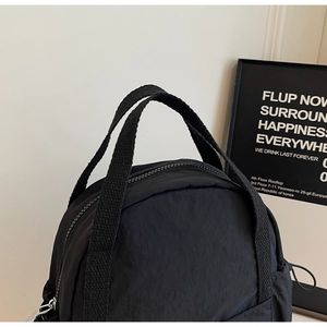 Détail du sac à dos en nylon noir montrant la fermeture éclair et les poignées