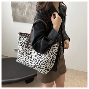 Close-up of leopard print tote bag with brown leather handles and gold rivet details