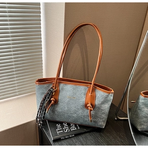 Detail of grey felt tote bag with brown leather trim and chic gold logo on book