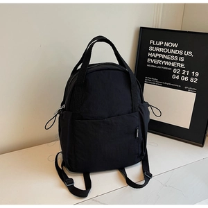 Détail du sac à dos noir en nylon avec doubles poignées et poches latérales à cordon