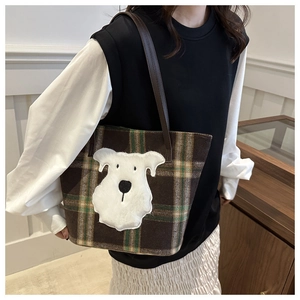 Detail of checkered plaid tote bag with plush puppy patch and leather shoulder straps