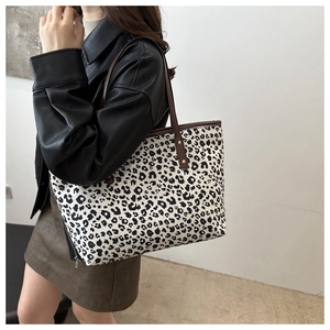 Detailed macro view of a leopard print tote bag with brown leather straps on a model