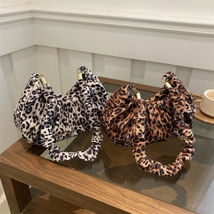 Detail of leopard print pleated bags with gold metal hardware on a glass table