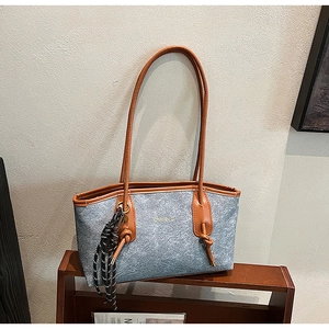 Detailed macro view of gray felt tote bag with brown leather handles and gold lettering