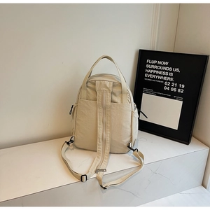 Détail du sac à dos en nylon beige avec fermeture éclair antivol sur le panneau arrière