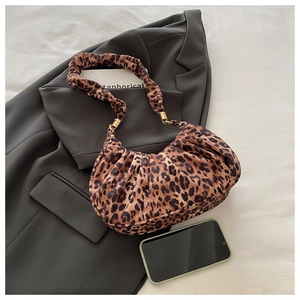 Detail of leopard print pleated shoulder bag with gold hardware on a stylish suit
