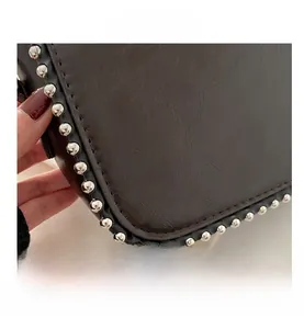 Detailed macro view showing silver rivets and high-quality leather texture on dark brown bag
