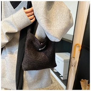 Gros plan d'un sac à main noir en peluche avec étiquette blanche porté par un mannequin