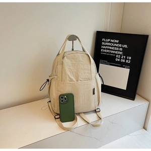 Vue latérale du sac à dos en nylon beige avec poche à cordon et smartphone comme référence de taille