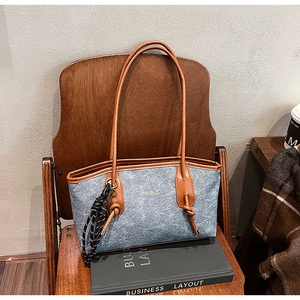 Detail view of grey felt tote bag featuring brown faux leather trim and rope charm decoration