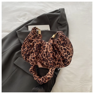Detail of leopard print handbag featuring pleated handle and gold metallic cylinder hardware