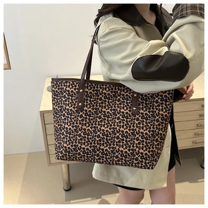 Detailed view of the leopard print tote bag with brown leather straps and gold rivets