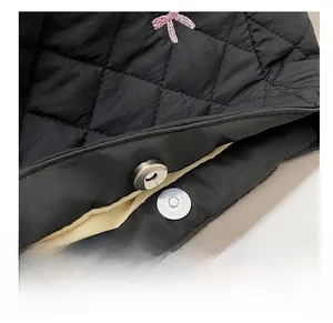 Détail du fermoir magnétique argenté sur sac matelassé noir avec nœud rose