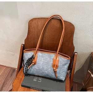 Detail of grey felt tote bag with brown leather handles on a vintage wooden chair