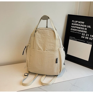 Vue détaillée du sac à dos en nylon beige avec poche latérale à cordon et doubles poignées