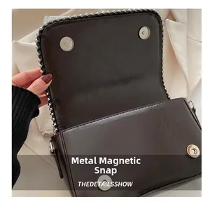 Detail showing magnetic snap closures and silver rivets on a dark brown leather chain bag