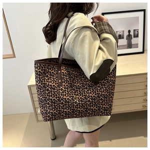 Detailed side view of the large leopard print tote bag with brown leather handles