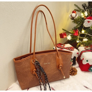 Close-up of brown suede tote bag with knotted side details and festive holiday backdrop