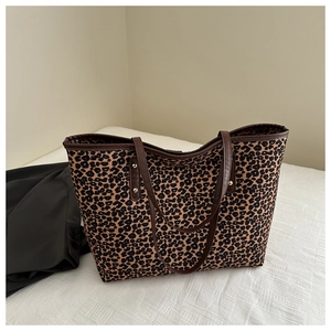 Detail of leopard print tote bag with brown leather handles and metal rivet reinforcement