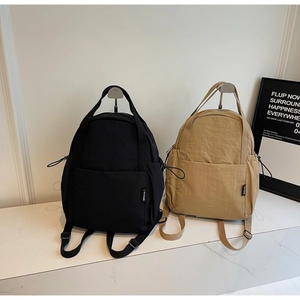 Détail de sacs à dos en nylon noir et kaki avec cordon latéral et étiquettes de marque