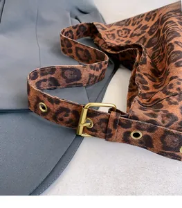 Detail of vintage leopard print tote bag featuring a gold buckle and metal eyelets