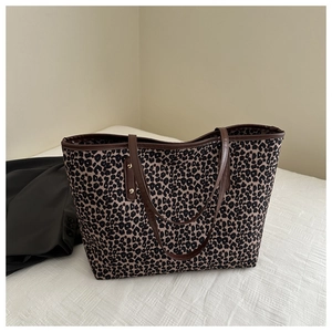 Detailed close-up of leopard print tote bag with brown leather handles and metal rivets