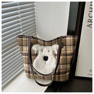 Close-up of brown-green plaid tote bag with plush schnauzer dog patch and leather straps